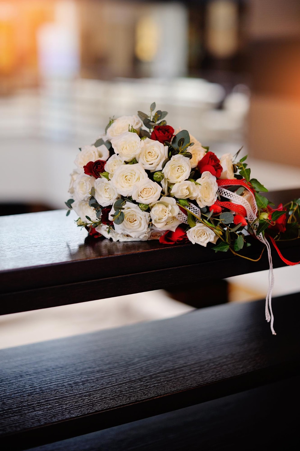 Blumenstrauß mit weißen und roten Rosen auf einer Kirchenbank – Blumenschmuck bei einer Erdbestattung bei Pietät Mayer Frankfurt