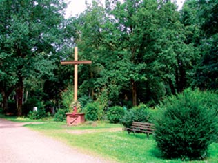 Kreuz auf einem gepflegten Weg in einer Parklandschaft