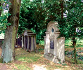 Grabstätte mit alter Steinstele im schattigen Friedhofsbereich